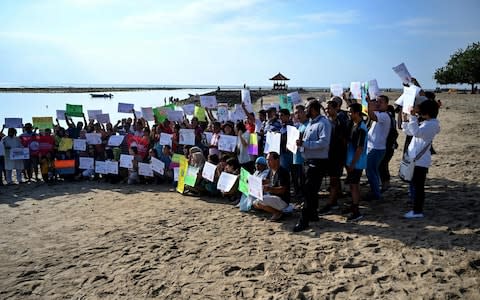 People display placards during a rally as part of a global climate change campaign at Sanur beach on Indonesia's resort island of Bali - Credit: AFP