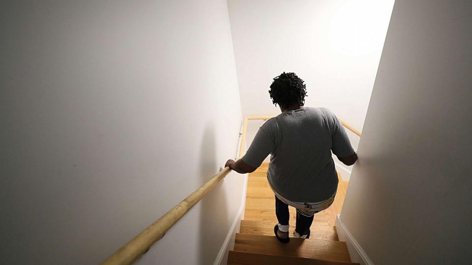 PHOTO: A person suffering from long covid walks down the steps leading from her apartment, in Worcester, Mass., Aug. 23, 2023. (Boston Globe via Getty Images)