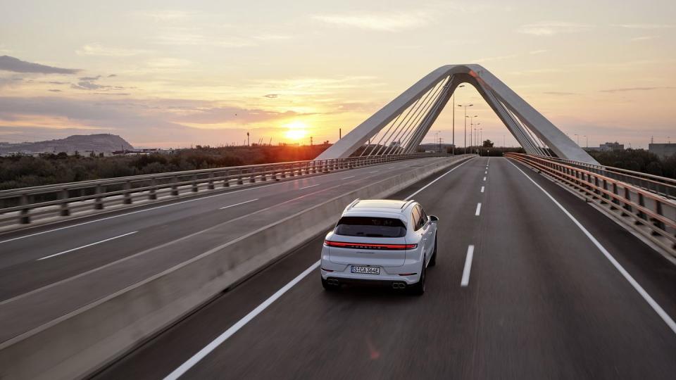 overview shot of the 2024 porsche cayenne turbo e hybrid driving over a bridge at dusk