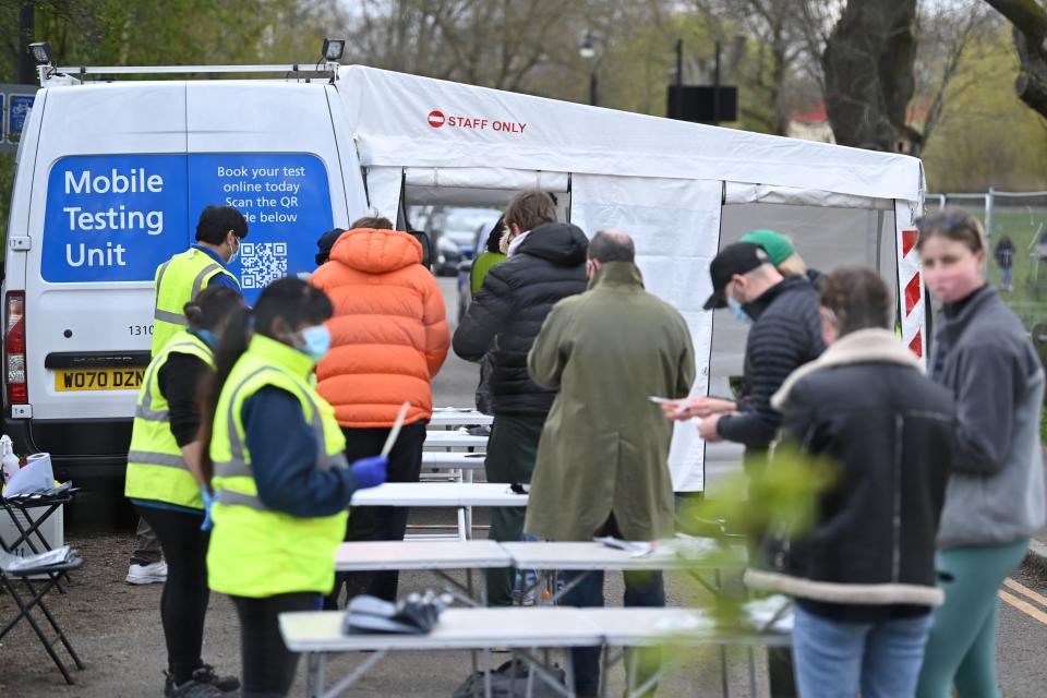 People check their paper-work as they queue to take a Covid-19 test at a mobile novel coronavirus testing centre on Clapham Common in south London, on April 13, 2021. - Britain said late Monday it had hit a target to offer a coronavirus vaccine first dose to all over-50s by mid-April, as England's lockdown-weary population toasted a significant easing of restrictions with early morning pints and much-needed haircuts. (Photo by DANIEL LEAL-OLIVAS / AFP) (Photo by DANIEL LEAL-OLIVAS/AFP via Getty Images)