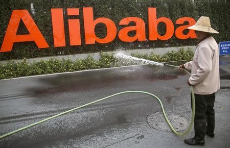 A cleaner waters the flowers below a logo of Alibaba (China) Technology Co. Ltd at the company's headquarters on the outskirts of Hangzhou, Zhejiang province November 21, 2013. REUTERS/Chance Chan