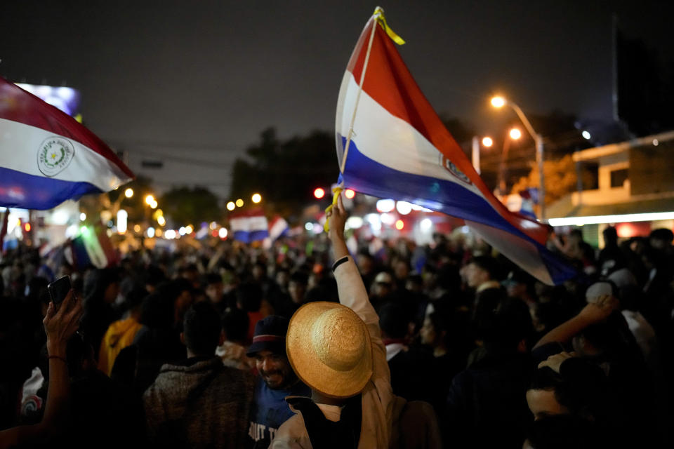 A demonstrator waves a Paraguayan national flag during a protest, where people have gathered claiming fraud in the general election, in Asuncion, Paraguay Tuesday, May 2, 2023. Paraguayans voted on Sunday to keep the long-ruling Colorado Party in power for five more years, backing its presidential candidate and giving it majorities in both houses of Congress. (AP Photo/Jorge Saenz)