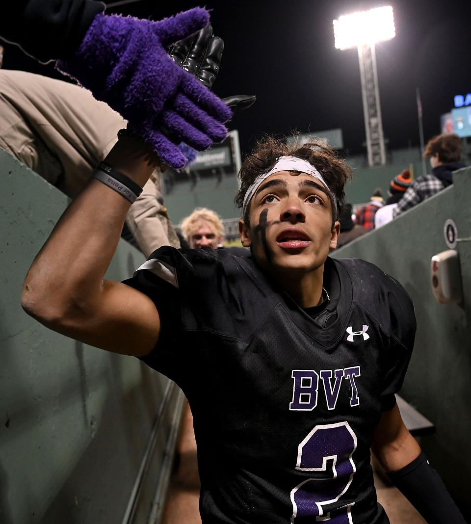 Blackstone Valley Tech's Josh Mateo accepts congratulations from fans as he exits the Fenway Park playing field after scoring three touchdowns against Nipmuc Regional, Nov. 24, 2021.  