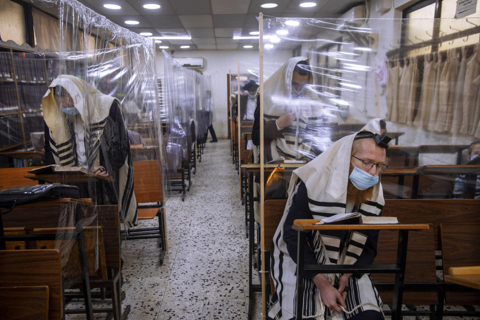 Ultra-Orthodox Jews wear face masks and are separated by plastic partitions, during a morning prayer in a synagogue separated by plastic partitions, during a nationwide three-week lockdown to curb the spread of the coronavirus, in Bnei Brak, Israel, Monday, Sept 21, 2020. (AP Photo/Oded Balilty)