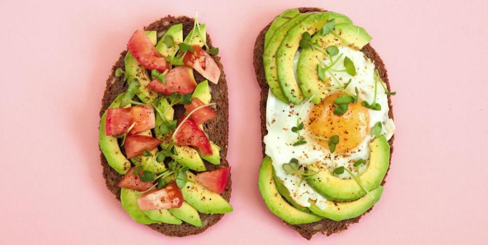 surprising sources of fruit and veg, two toasts of dark bread with avocado slices, chopped tomatoes, fried egg and microgreen breakfast concept top view, pink background healthy food