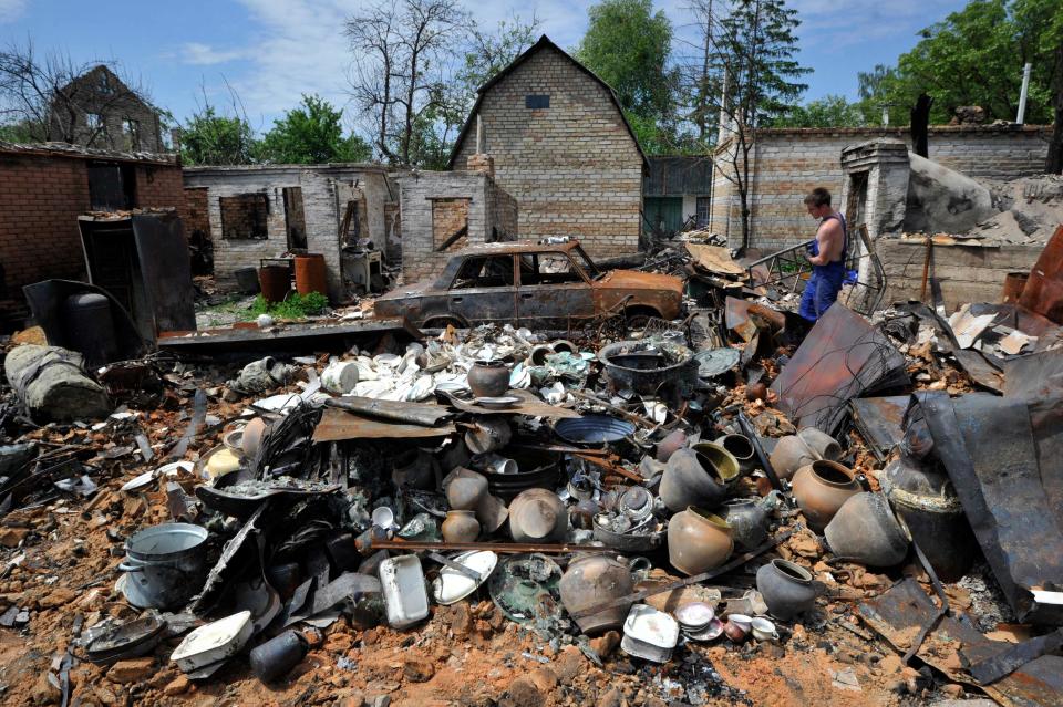 A man cleans up debris after his house was destroyed by shelling in the village of Moshchun, Ukraine, on June 2.