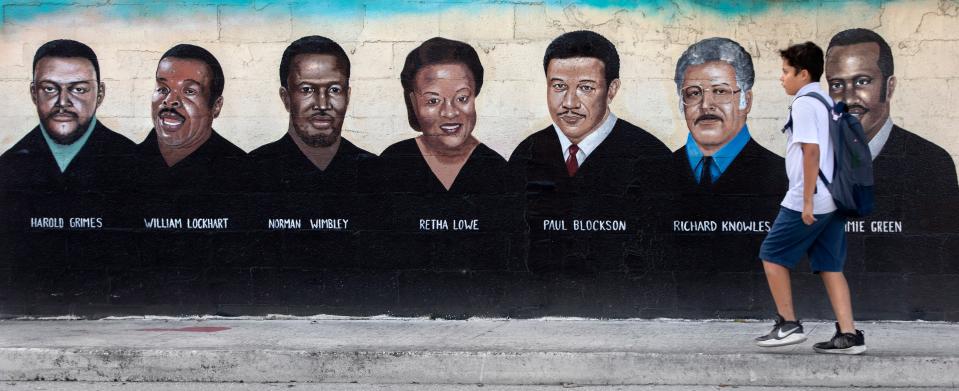 Francisco Lopez walks by a mural painted on the Wall of Unity in Lake Worth Beach, Florida on January 10, 2024.