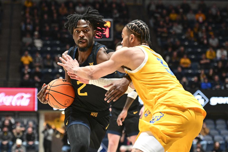 West Virginia guard Kobe Johnson (2) protects the ball from Pittsburgh guard Ishmael Leggett (5) during the first half of an NCAA college basketball game, Wednesday, Dec. 6, 2023, in Morgantown, W.V. (William Wotring/The Dominion-Post via AP)