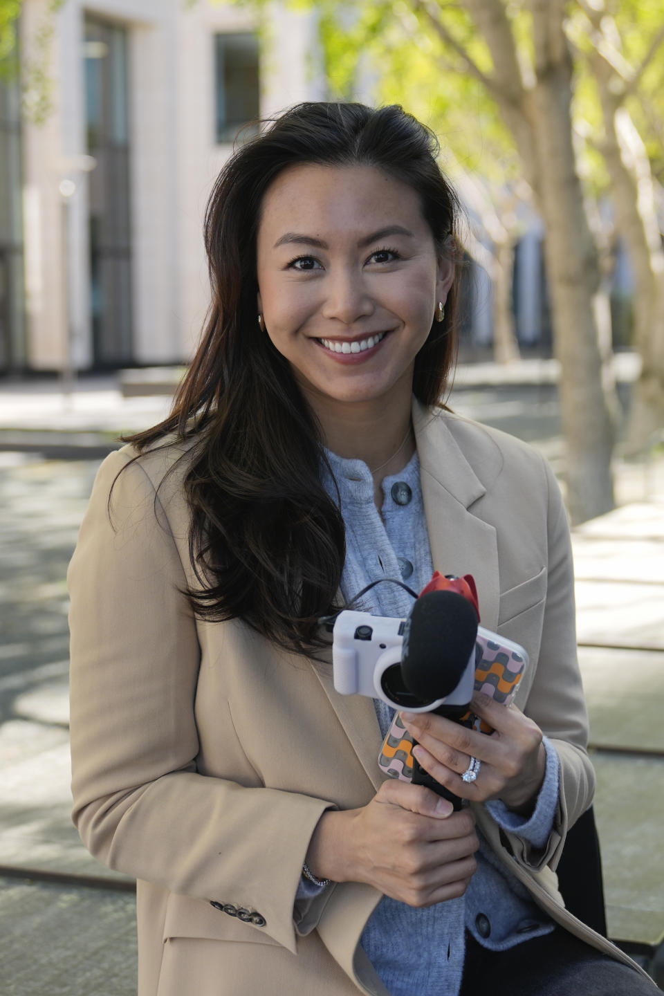 Content creator Cynthia Huang Wang poses with her phone and camera in San Francisco, Monday, April 8, 2024. Despite a strong job market, there are still thousands of people who have found themselves out of work across industries stretching from tech to retail to media. But rather than trying to find another job in their old role, some workers are turning to online content creation. (AP Photo/Eric Risberg)