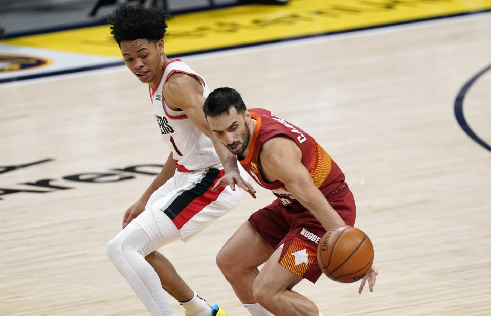 Denver Nuggets guard Facundo Campazzo, front, reaches out for a loose ball as Portland Trail Blazers guard Anfernee Simons in the first half of an NBA basketball game on Tuesday, Feb. 23, 2021, in Denver. (AP Photo/David Zalubowski)