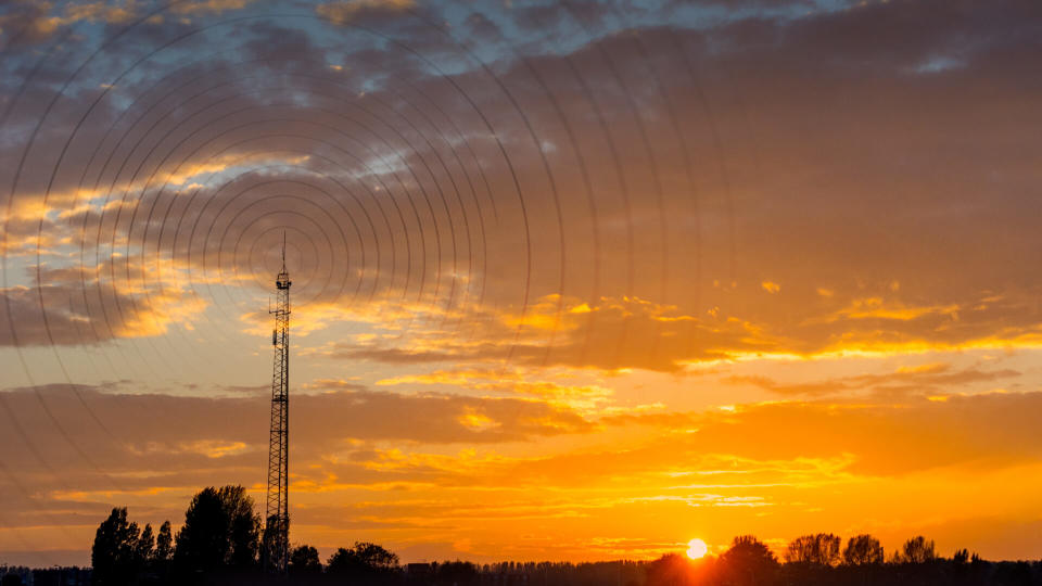 Radio waves escaping from gsm tower   visualisation at sunset in rural area.