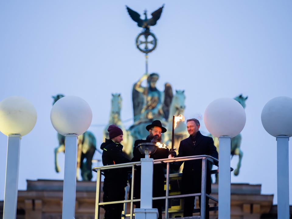 Christian Lindner (FDP, r), Federal Minister of Finance, and Rabbi Yehuda Teichtal (M), Chairman of the Chabad Jewish Education Center, light the first light on the Hanukkah candelabrum