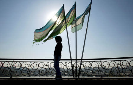 A girl is silhouetted against the sun standing next to Uzbek flags in Tashkent November 5, 2005. REUTERS/Shamil Zhumatov/File Photo