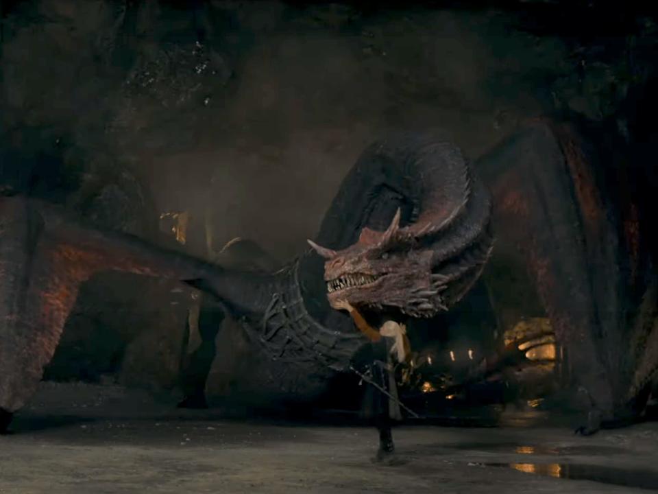 A man beside a massive dragon with red and black scales.
