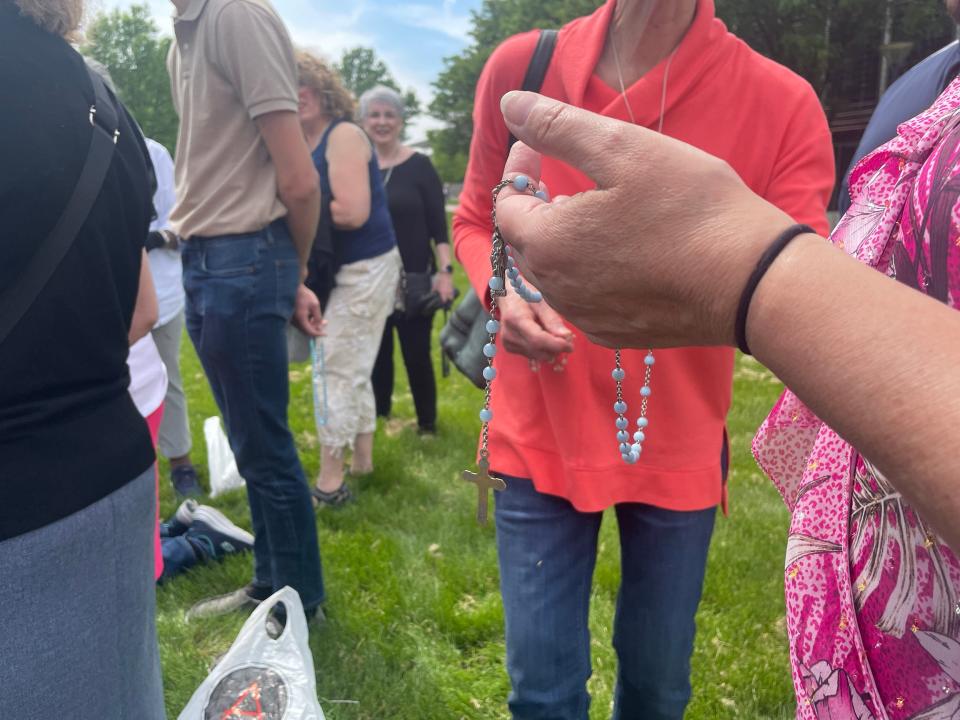 A woman holds a rosary while reciting The Hail Mary outside of a drag story hour Sunday, May 21 at the Des Moines Central Public Library.