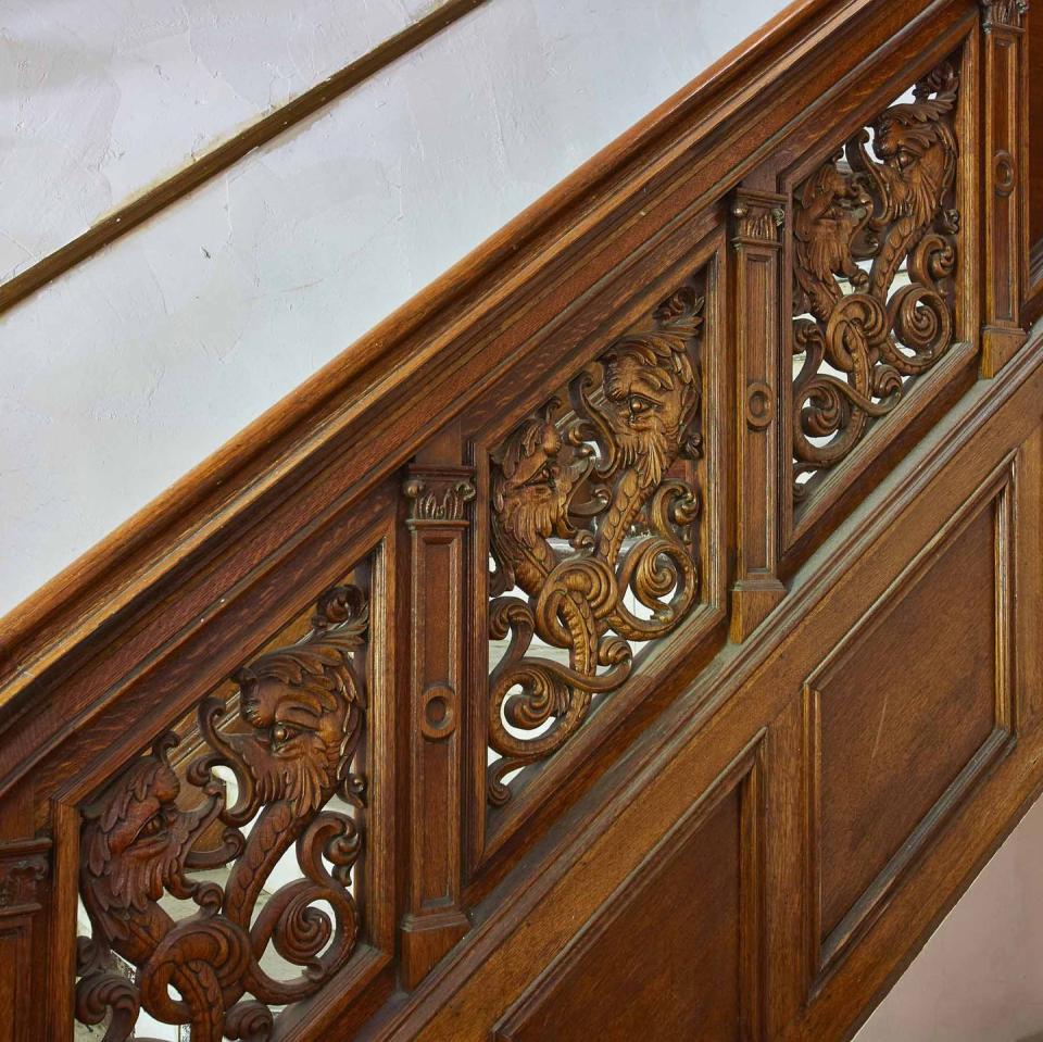 The foyer has a baronial wood staircase featuring ornate carved panels.