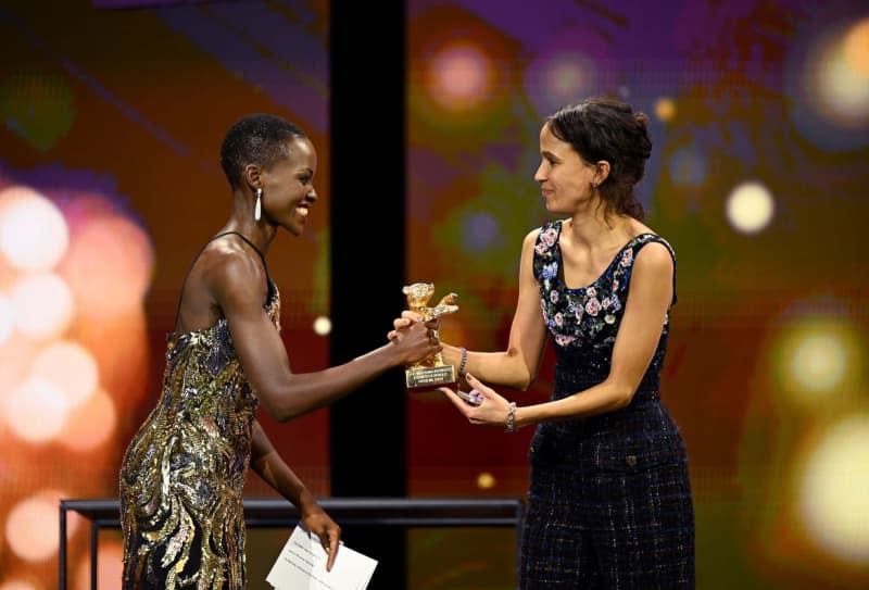 Lupita Nyong'o, President of the International Jury of the Berlinale 2024, presents director Mati Diop with a Golden Bear in the Best Film category on stage during the award ceremony at the closing gala in the Berlinale Palast. Monika Skolimowska/dpa