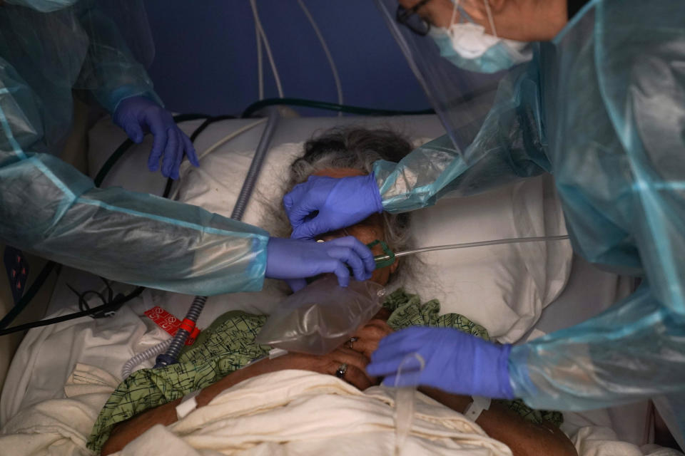 Two nurses put a ventilator on a patient in a COVID-19 unit at St. Joseph Hospital in Orange, Calif. Thursday, Jan. 7, 2021. California health authorities reported Thursday a record two-day total of 1,042 coronavirus deaths as many hospitals strain under unprecedented caseloads. (AP Photo/Jae C. Hong)