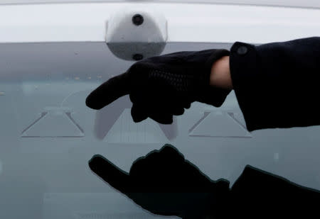 A man points out a camera sensor on a self-driving car at the Renesas Electronics autonomous vehicle test track in Stratford, Ontario, Canada, March 7, 2018. REUTERS/Mark Blinch