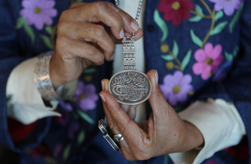 In this Thursday Nov. 7, 2013 photo, Egyptian jewelry designer Azza Fahmy shows her necklace designed by herself while talking with an Associated Press reporter in her hotel room window in Dubai, United Arab Emirates. Fahmy, who has been approached by a massive project called the Dubai Design District, or D3, as an adviser, is an icon among young Arab artisans for successfully infusing Egyptian and Islamic art into wearable, modern pieces. She created a line of jewelry for the British Museum inspired by the Muslim Hajj pilgrimage, and her jewelry will be on the runway Sunday, Feb. 16, 2014, during London's Fashion Week, for designer Matthew Williamson's show. (AP Photo/Kamran Jebreili)