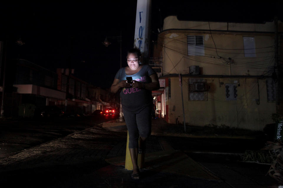 A woman uses her cell phone on a San Juan, Puerto Rico, street during a blackout on Sept. 25. (Photo: Alvin Baez/Reuters)