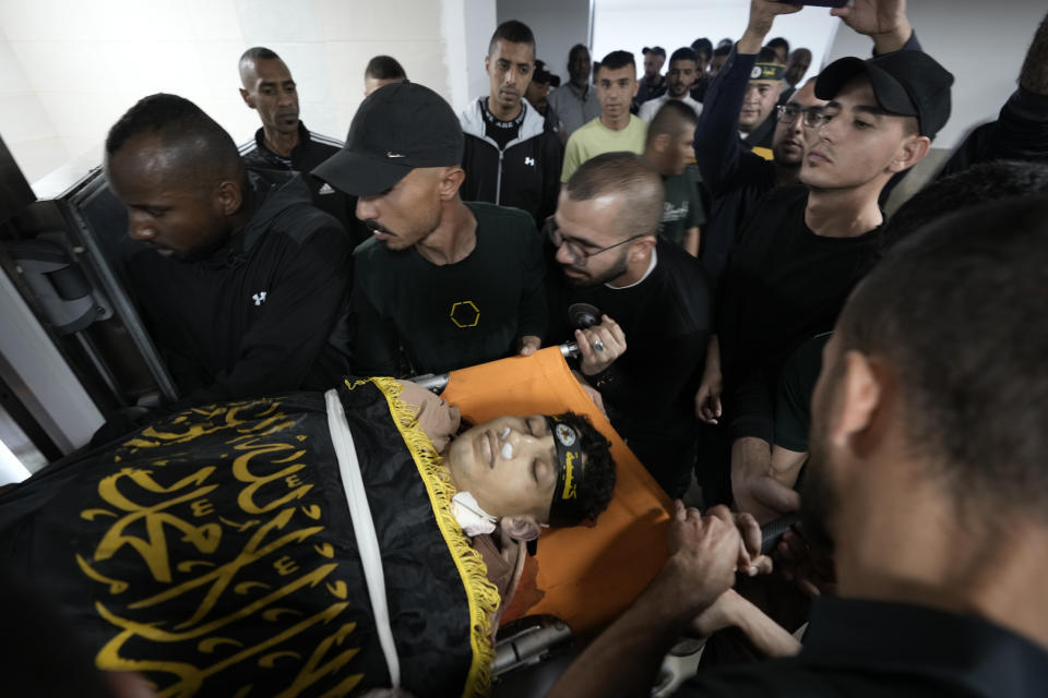 Relatives take a last look at Ahmed Assaf, 19, draped in the flag of Islamic Jihad, one of two Palestinians killed by Israeli forces in Qabatiya, near the West Bank city of Jenin, Wednesday, May 10, 2023. The Israeli military said that Palestinian gunmen opened fire at troops in the Palestinian town of Qabatiya in the northern West Bank during an army raid. Troops returned fire, killing the two men, and confiscated their firearms, it said. (AP Photo/Majdi Mohammed)