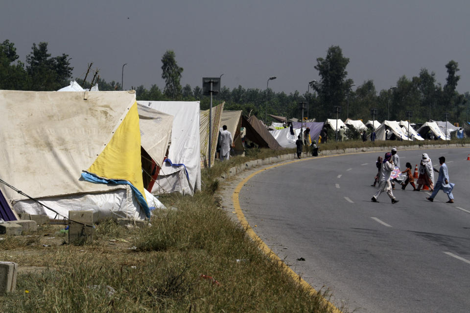 Displaced families take refuge on a roadside after fleeing their flood-hit homes, in Charsadda, Pakistan, Monday, Aug. 29, 2022. International aid was reaching Pakistan on Monday, as the military and volunteers desperately tried to evacuate many thousands stranded by widespread flooding driven by "monster monsoons" that have claimed more than 1,000 lives this summer. (AP Photo/Mohammad Sajjad)