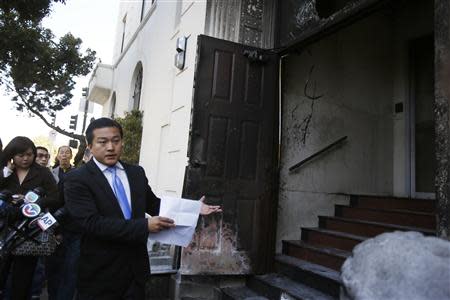 Wang Chuan, a spokesman for the Chinese consulate in San Francisco, points to a damaged door during a news conference after an unidentified person set fire in San Francisco, California January 2, 2014. REUTERS/Stephen Lam