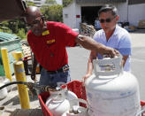 <p>City Mill hardware store sales associate Thom West, left, fills up several propane tanks for Tony Cao, Wednesday, Aug. 22, 2018, in Honolulu. Cao said he waited nearly two hours in line for propane. Although he already stocked up on fresh food, Cao the most important things to have during Hurricane Lane were Spam and Vienna savage as you don’t need to cook them. (Photo: Marco Garcia/AP) </p>