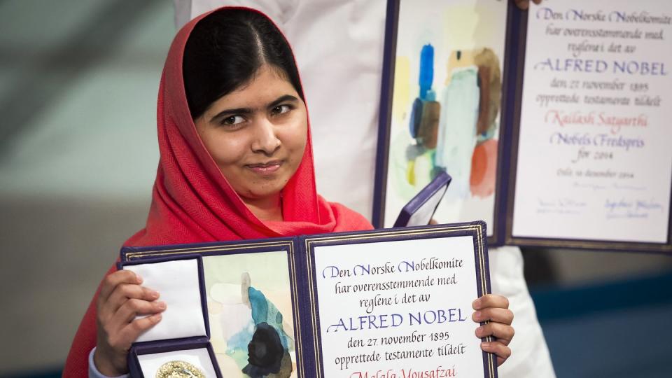 malala yousafzai holding a medal and diploma open for photos