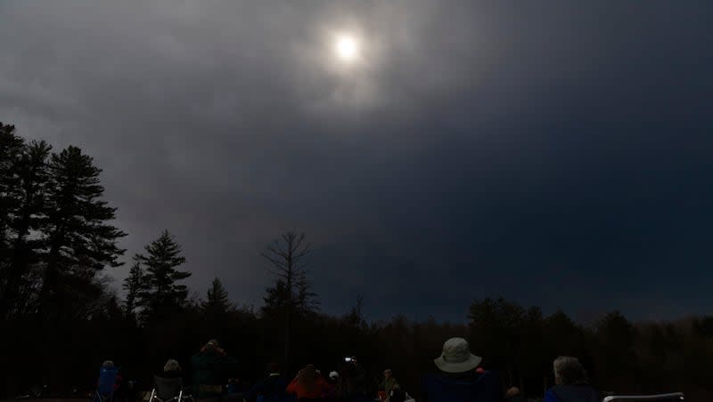 People gather to watch the total solar eclipse, moments before it reaches totality, from Agers Falls in Lyons Falls, N.Y., Monday, April 8, 2024.