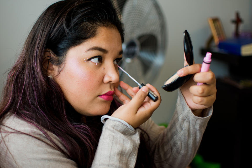 A woman is doing her eye makeup