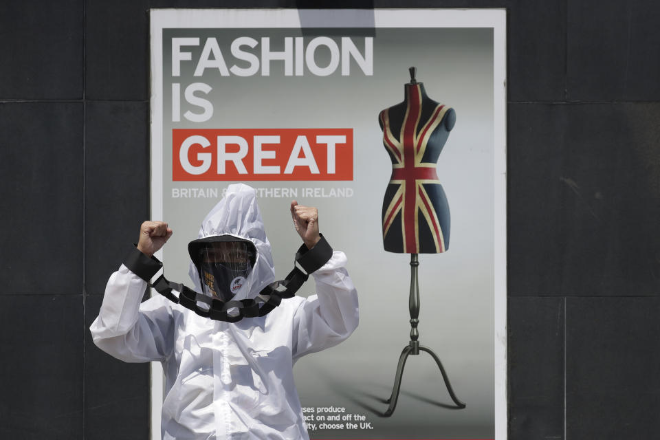 A protester dressed in protective suit with hands tied with mock chains shouts slogans during a rally against the G7 summit outside the British Embassy in Taguig, Philippines on Friday, June 11, 2021. The group called on G7 Summit member nations for debt cancellation for poor countries facing difficulties due to the COVID-19 pandemic. (AP Photo/Aaron Favila)