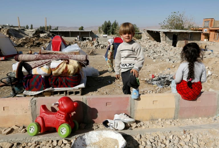 Iranian children are seen next to the rubble of their home in Kouik on November 15, 2017 after a major earthquake