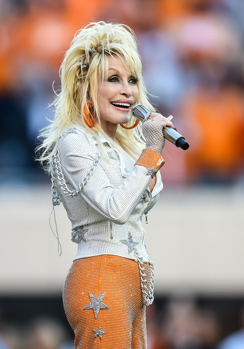 Dolly Parton sings onstage, wearing a bedazzled outfit with star motifs