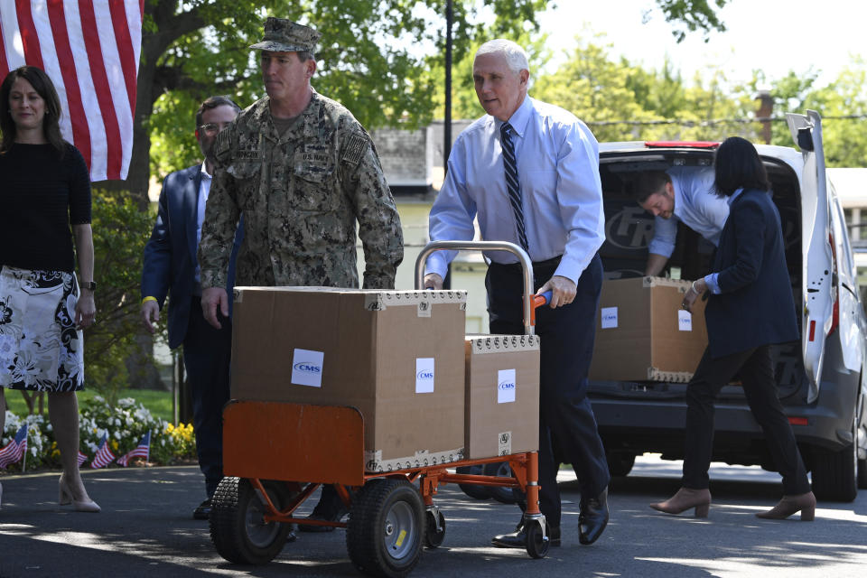 FILE - In this Thursday, May 7, 2020 file photo, Vice President Mike Pence, center, pushes a cart with boxes of PPE from FEMA at the Woodbine Rehabilitation and Healthcare Center in Alexandria, Va. On Friday, May 8, 2020, The Associated Press reported on stories circulating online incorrectly asserting Pence delivered empty boxes of personal protective equipment to the nursing home for a publicity stunt. The claim went viral on social media after the show “Jimmy Kimmel Live!” published a selectively edited clip of Pence joking about carrying empty boxes “for the camera.” The full C-Span video shows Pence delivering boxes of the equipment and then returning to a van containing more boxes. A microphone captures Pence talking with a person supervising. “Those are empty, sir. We’re good to go,” the person supervising says. Pence responds, “Can I carry the empty ones, just for the camera?” The person replies, “Absolutely.” Pence then begins laughing and shuts the van doors. He does not take any of the empty boxes. (AP Photo/Susan Walsh)