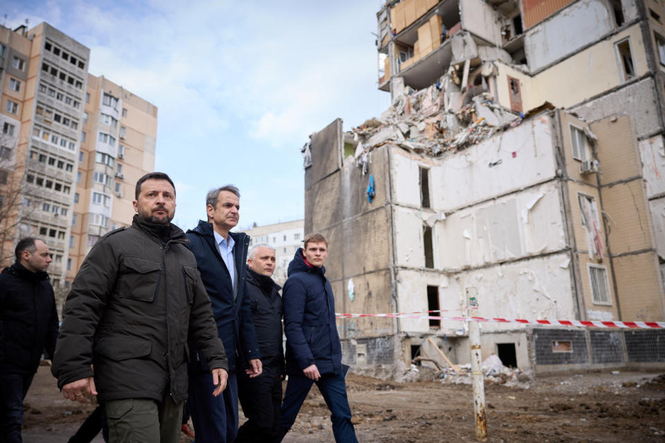 烏克蘭總統澤倫斯基（前左一）和希臘總理米佐塔基斯（前左二）6日在烏克蘭敖德薩參觀了前一天無人機襲擊受害者的臨時紀念碑，該攻擊導致一棟公寓大樓嚴重受損。（Ukrainian Presidential Press Service/Handout/路透社）