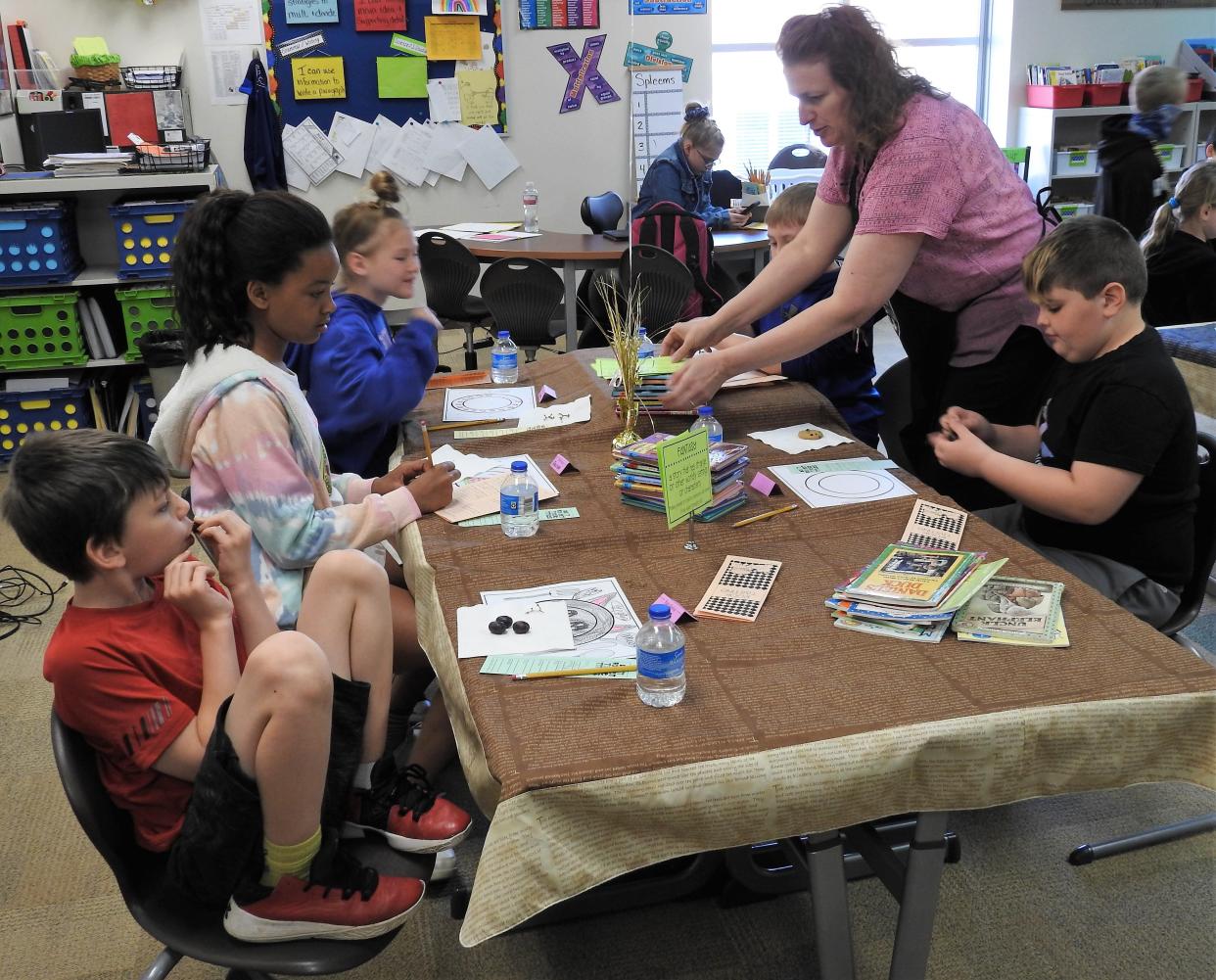 Amy Unkefer, third grade teacher at Coshocton Elementary School, passes out a new set of books to students during a book tasting activity. Students are in an imaginary café and having treats while checking out books to see what ones they might like to read in full.