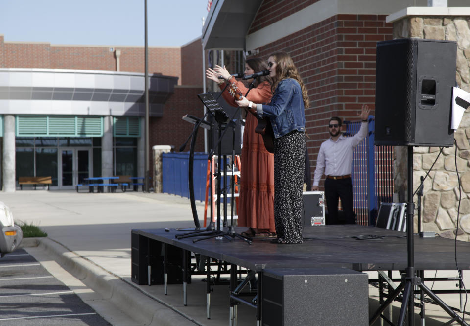 Kensley Husband and Chelsea Locklear lead the congregation in "Jesus Paid It All" during a drive-in Easter service held by the Relevant Church on Saturday, April 11, 2020, at the YMCA parking lot in Clover, S.C. The coronavirus has pushed the church members out of their usual church setting. Impending bad weather made the church hold its Easter Sunday service on Saturday. (AP Photo/Sarah Blake Morgan)