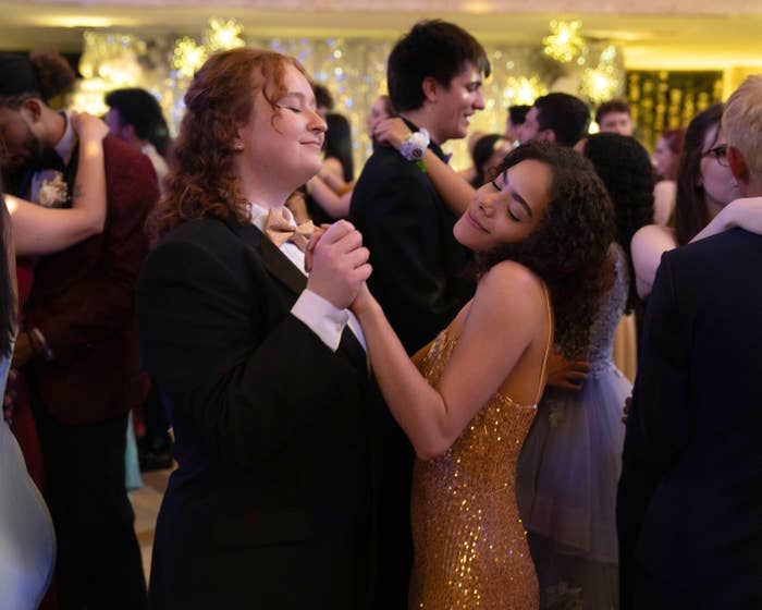 Julia Lester, Antonia Gentry dancing in formalwear at a prom event with others dancing behind them