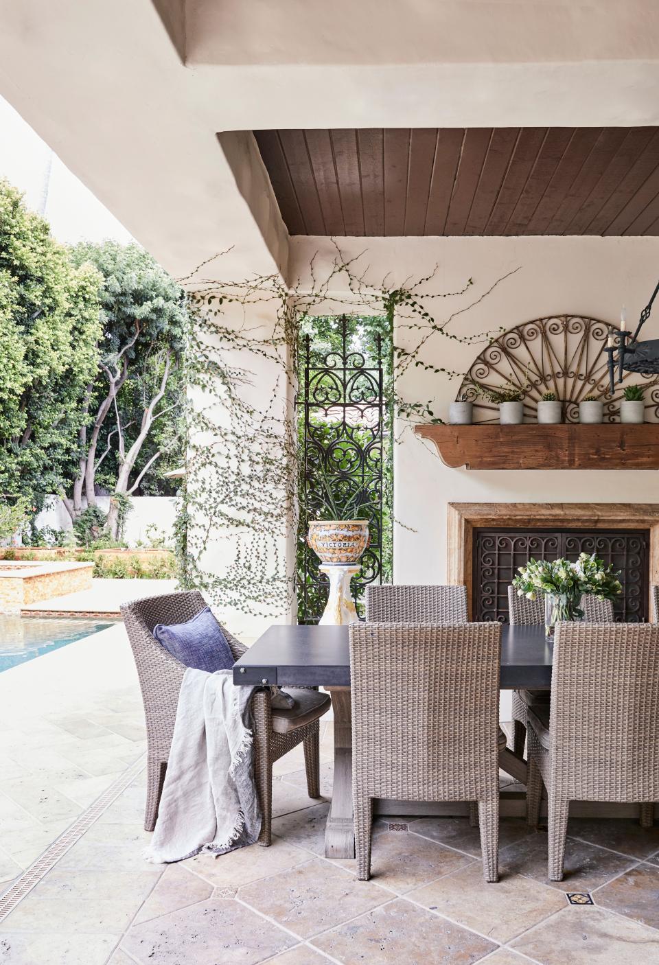 An outdoor dining room with a table and chairs from Restoration Hardware overlooks the pool.