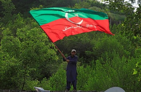 A supporter of cricket star-turned-politician Imran Khan, chairman of Pakistan Tehreek-e-Insaf (PTI), waves a party flag as he celebrates outside his residence in Islamabad, Pakistan, a day after polling in the general election, July 26, 2018. REUTERS/Faisal Mahmood