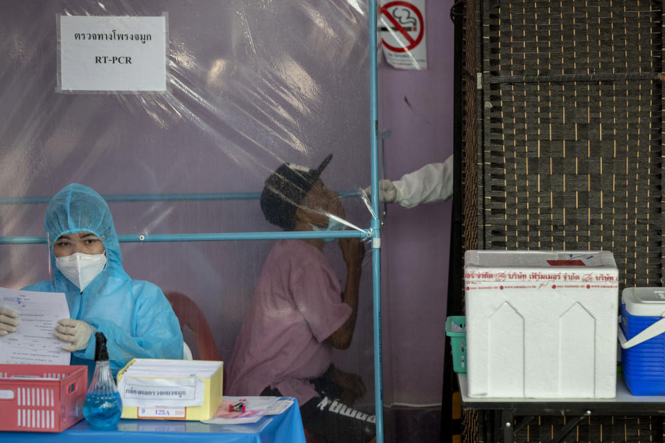 A migrant worker sits behind a plastic pertaining board to discharge nasal-sample to screen COVID-19 at an outdoor testing center in Samut Sakhon, South of Bangkok, Thailand Monday, Jan. 4, 2021. For much of 2020, Thailand had the coronavirus under control. After a strict nationwide lockdown in April and May, the number of new local infections dropped to zero, where they remained for the next six months. However, a new outbreak discovered in mid-December threatens to put Thailand back where it was in the toughest days of early 2020. (AP Photo/Gemunu Amarasinghe)