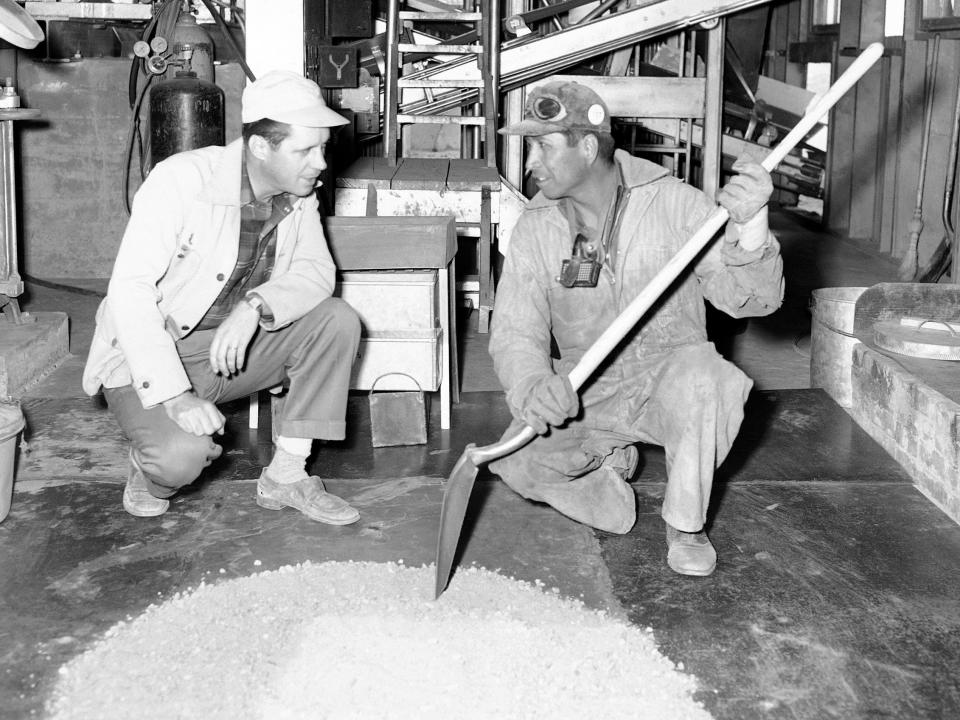 A Navajo man and a supervisor inspect some ore in a uranium plant in 1952.