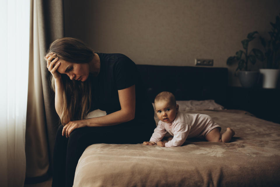 A mom looks overwhelmed, while caring for her baby alone