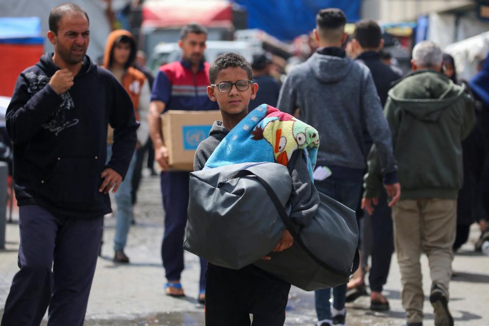 Displaced Palestinians in Rafah carry their belongings as they prepare to leave following an evacuation order by the Israeli army on May 6, 2024.