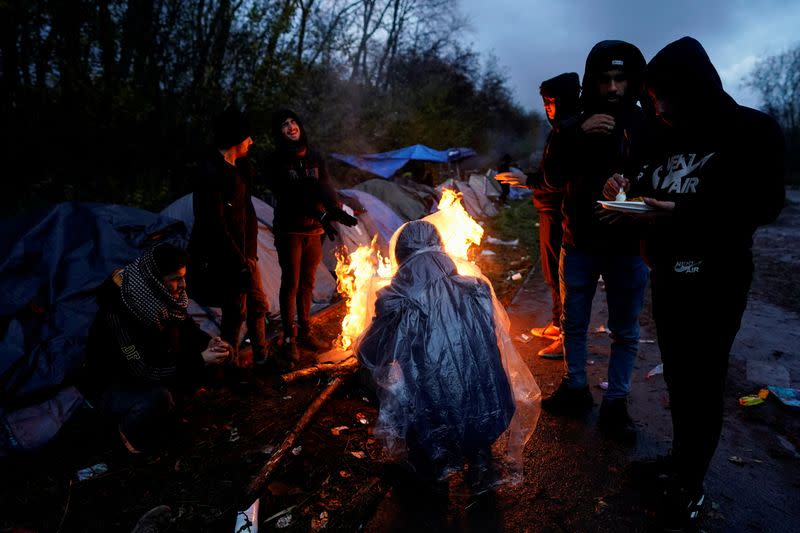 FILE PHOTO: Kurdish migrants stand near a fire at a makeshift camp in Loon-Plage near Dunkirk, France,