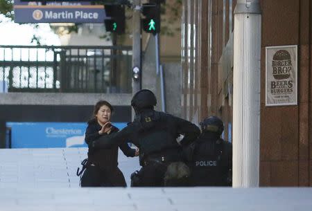 A hostage runs towards a police officer outside Lindt cafe, where other hostages are being held, in Martin Place in central Sydney December 15, 2014. REUTERS/Jason Reed