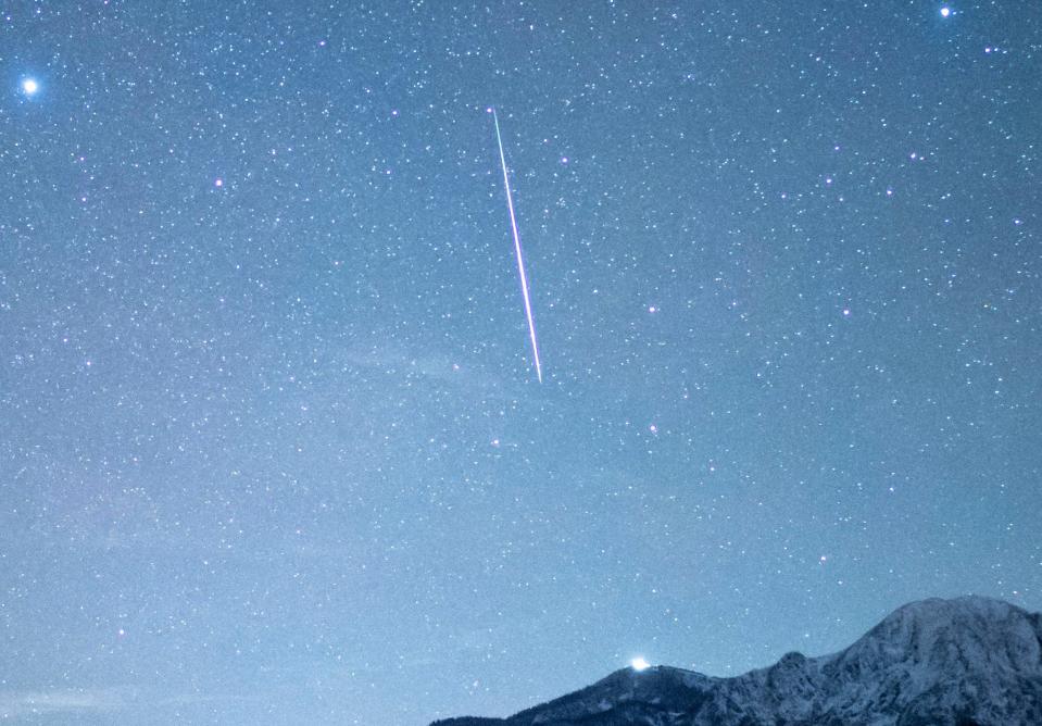 A shooting star can be seen during the Geminid meteor shower in the starry sky in December 2020.
