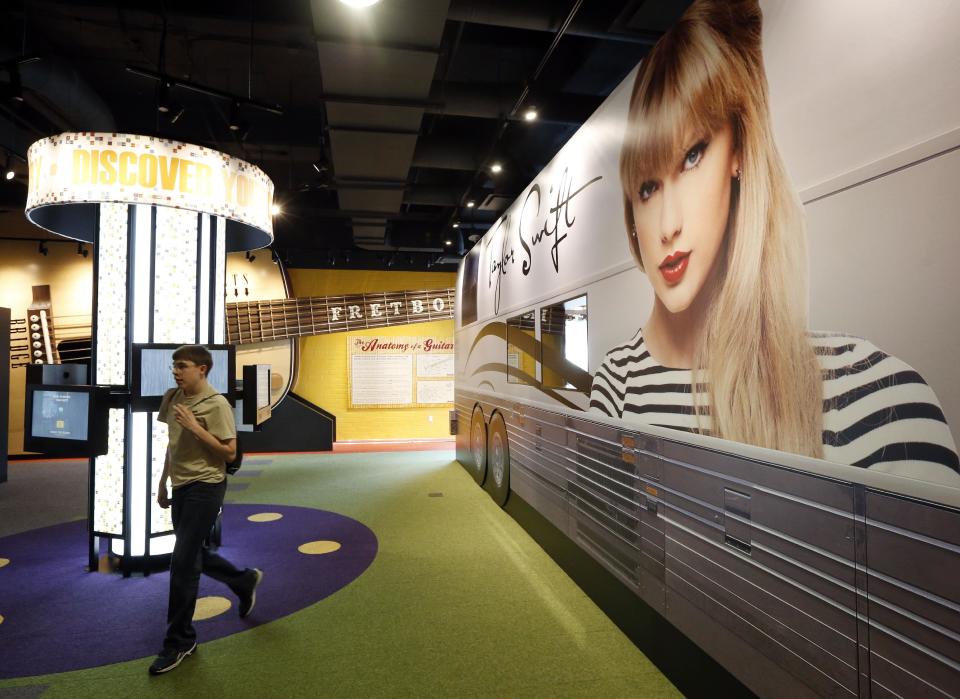 In this April 10, 2014, photo, a visitor walks past a 75-foot replica of Taylor Swift’s tour bus in a new section of the Country Music Hall of Fame and Museum in Nashville, Tenn. Educational exhibits are part of the $100 million expansion. (AP Photo/Mark Humphrey)